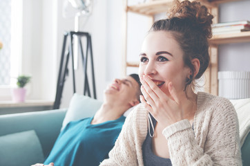 Couple at home enjoying on sofa and laughing while watching something