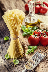 Spaghetti.Spaghetti tomatoes basil olive oil parmesan cheese and mushrooms on very old oak board. Mediterrannean cuisine and ingredients.