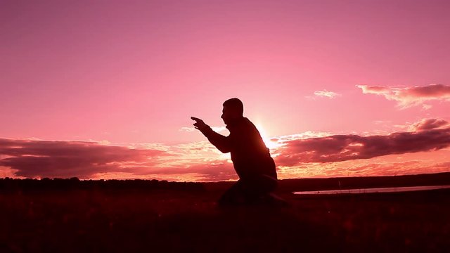Silhouette of a man praying at sunset concept of religion. Image of silhouette man praying with sunset background