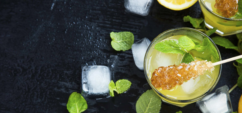 Lemon cocktails with mint and ice cubes on dark background, mojitos ingredients
