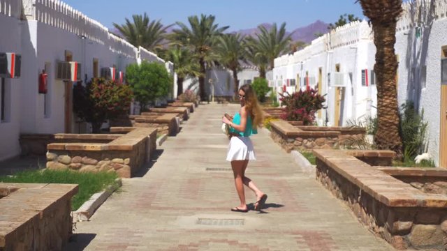 beautiful young blonde goes around traditional egyption buildings at bright summer day