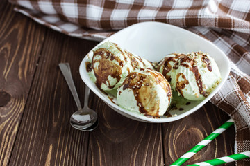 Pistachio ice cream with chocolate on a rustic background