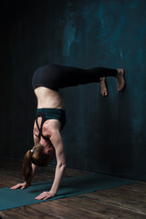 Sporty young woman practicing advanced yoga pose.