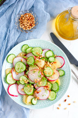Salad from potatoes, radishes, cucumbers with pine nuts, top view