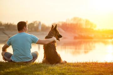 Relaxed man and dog enjoying summer sunset or sunrise