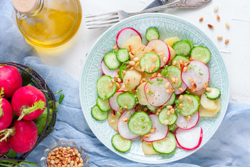 Salad from potatoes, radishes, cucumbers with pine nuts, top view