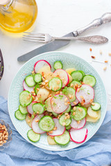 Salad from potatoes, radishes, cucumbers with pine nuts, top view