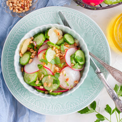 Salad from potatoes, radishes, cucumbers with pine nuts, top view, square