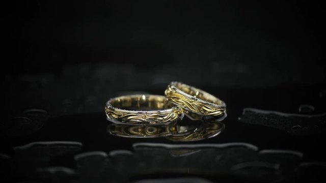 Gold Rings On Black Wet Surface On Black background