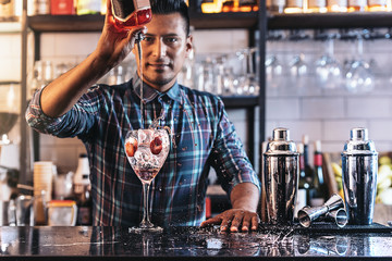 Barman is making cocktail at night club.