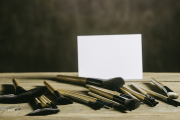 Makeup stuff with white blank paper on rustic table