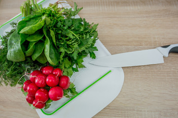 Greens and radishes on the kitchen board, knife
