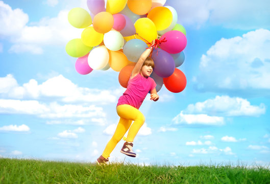 happy girl runing with colorfull balloons  on green meadow