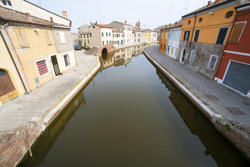 Fototapeta na wymiar View of the small Italian town Comacchio (Ferrara, Emilia Romagna region): traditional colored houses and canal for boats.