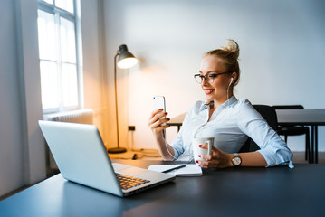Portrait of a young beautiful businesswomen enjoying coffee during work on portable laptop computer