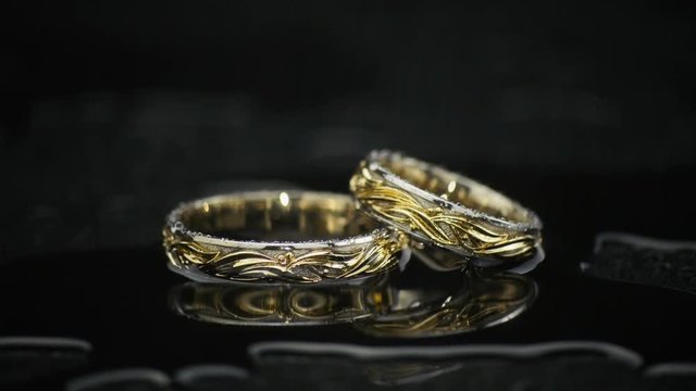Gold Rings On Black Wet Surface On Black Background