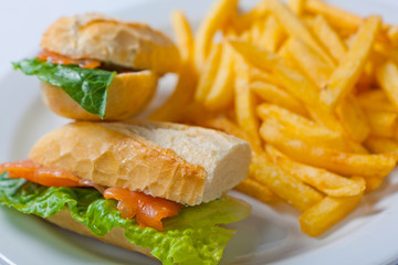 Sandwich with salmon, tomato, cheese and golden French fries potatoes