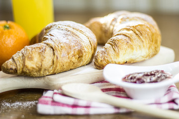 Croissants breakfast composition on kitchen table.