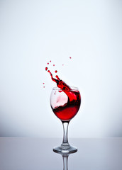 A glass with red wine and sprays.