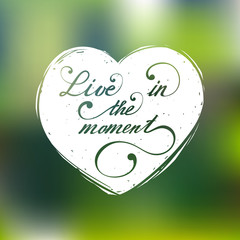 Live in the moment vector hand lettering inspirational typography poster in heart silhouette on blur background.