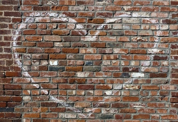 Outline of faded white heart painted on brick wall.