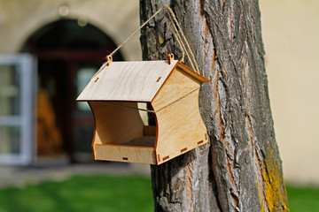 Empty wooden bird feeder hanging on a tree