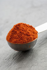 Ground chili pepper in a spoon on a dark background, macro shot, selective focus