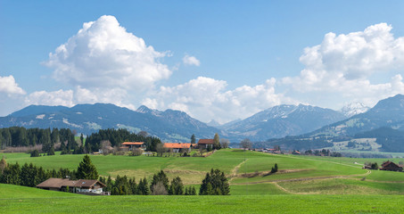 Fototapeta na wymiar Village surrounded by green forests and snow covered mountains