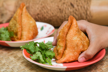 girl child holding fried samosa popular indian, asian and african deep fried snack with spicy chutney and mint. local street food in North India, Bombay, Kerala, Tamil Nadu