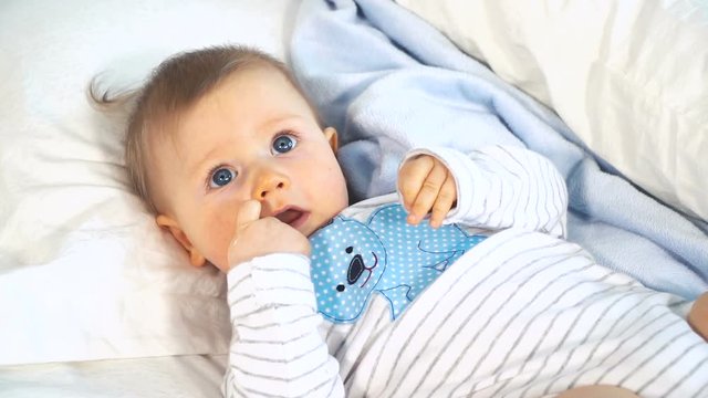 baby mit gro&szlig;en blauen augen und blonden haaren im bett