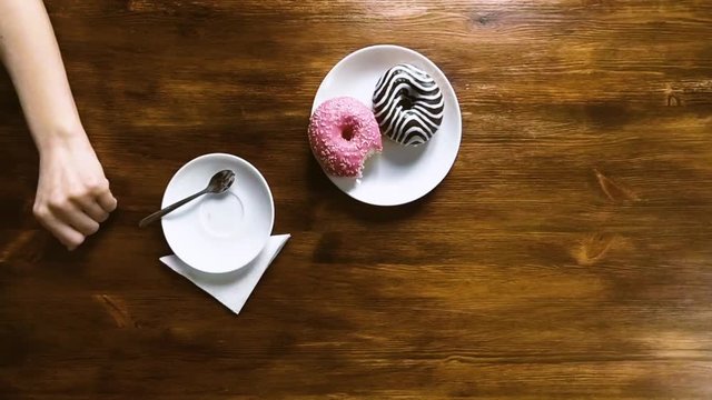 Young woman drinking coffee with donuts in cafe, top view, slow motion hd video