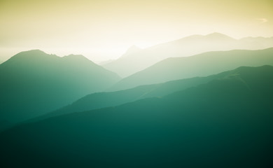 Naklejka premium A beautiful, colorful, abstract mountain landscape with a hot summer haze in warm green tonality. Decorative, artistic look.