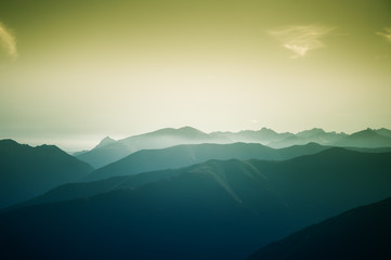 A beautiful, colorful, abstract mountain landscape with a hot summer haze in warm green tonality. Decorative, artistic look.