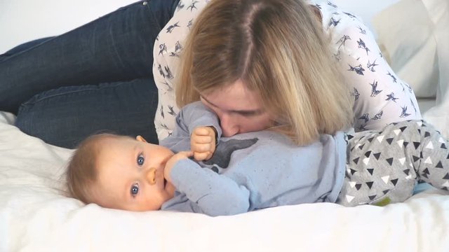 baby mit gro&szlig;en blauen augen und blonden haaren im bett kuschelt mit mama
