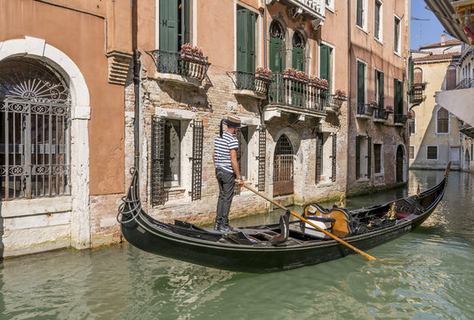 Gondolier standing on his gondola navigates near Calle Larga XXII Marzo on the Rio de San Moise' canal, Venice, Italy