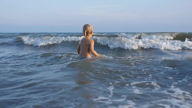 A little child playing with sea waves on summer vacation in slow motion x2