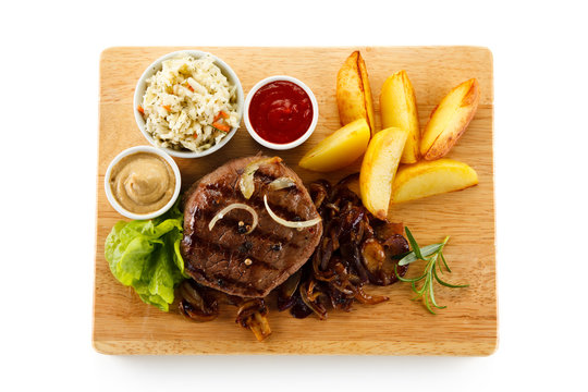 Steaks, baked potatoes and vegetable salad