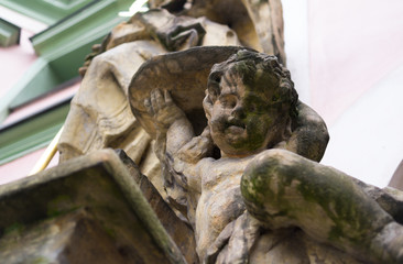 Cherub / Angel - baroque statue of saint little boy. Figural decoration of religious building, church. Sculpture is old and aged.