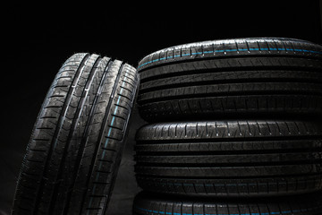Obraz premium Stack of brand new high performance car tires on clean low-key black studio background