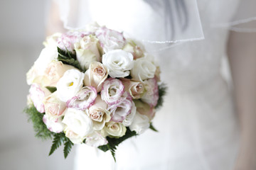 Mazzolinodi rose di vari colori in mano ad una sposa