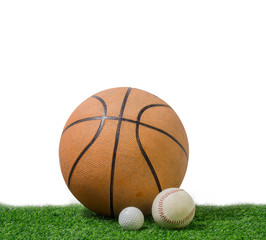 golf ball, baseball and basketball in green grass on white background.