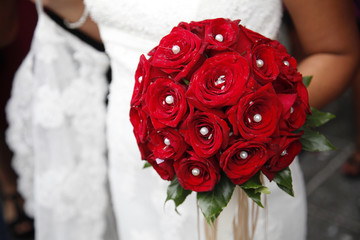 Mazzolino rosso con perle in mano a una sposa