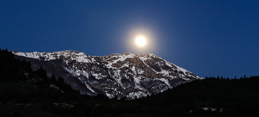 Fototapeta na wymiar moon rising over snowy mountain top
