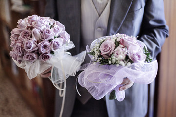 2 bouquet color lilla tenuti da uno sposo elegante