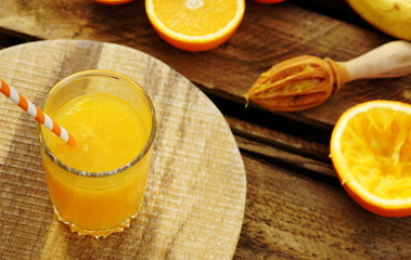 Freshly squeezed orange juice in glass with juicer on wooden board