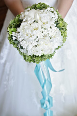 Composizione floreale bianca con fiocco azzurro tenuta da sposa