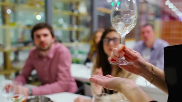 Close-up - sommelier shakes the white wine in glass on degustation