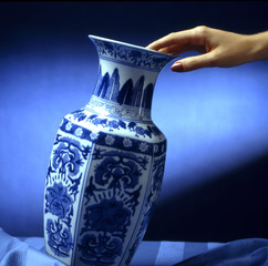 hand put a decorated ceramic vase on a table