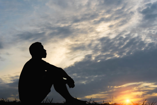Silhouette of a man sitdown with so sad in the sunset.