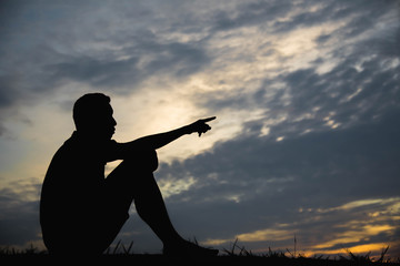 Silhouette of a man with hands point to sky in the sunset.